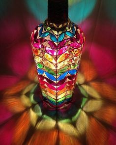 a multicolored glass vase sitting on top of a colorful tablecloth covered floor