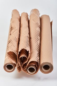 four rolls of brown paper sitting next to each other on top of a white surface