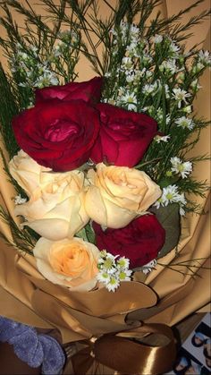 a bouquet of roses and daisies is wrapped in brown paper with a ribbon around it