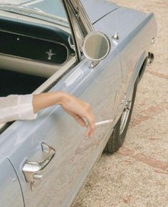 a woman leaning out the side door of a car with her hand on the handle