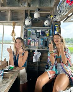 two women sitting at a table in front of a window and one is holding her hand up