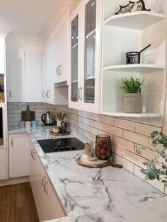 a kitchen with marble counter tops and white cabinets