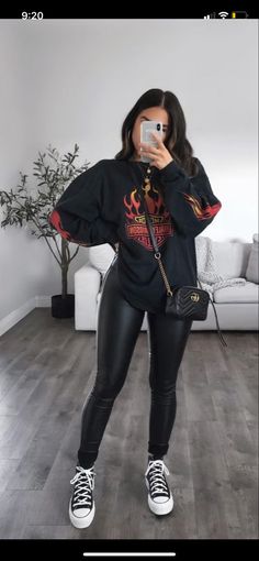 a woman taking a selfie in her living room wearing black leather leggings