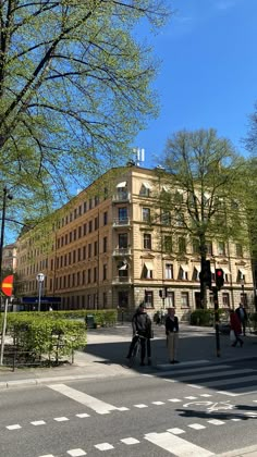 people walking across the street in front of an old building