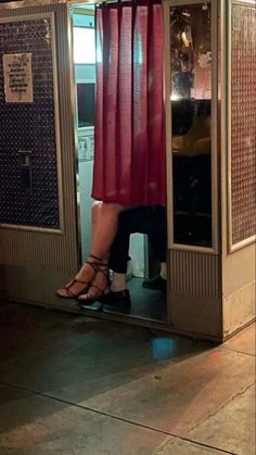 a woman is standing in a phone booth with her legs up and wearing high heels