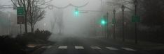 a foggy street with green traffic lights