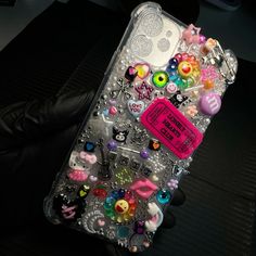 an iphone case with lots of different items on it and a pink tag that says hello kitty