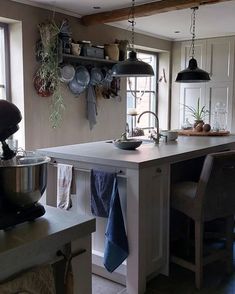 a kitchen with an island and hanging pots on the wall