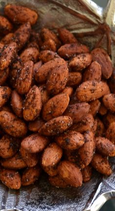 a pile of roasted peanuts sitting on top of a metal pan covered in brown stuff