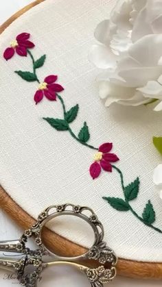 a pair of scissors sitting on top of a piece of fabric next to some flowers