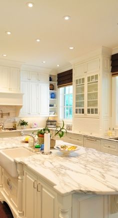 a large kitchen with white cabinets and marble counter tops, along with an island in the middle