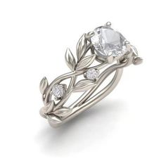 a blue sapphire and diamond ring with leaves on the band, set in white gold