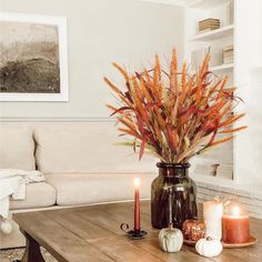 a table with candles and flowers in a vase on top of it next to a couch