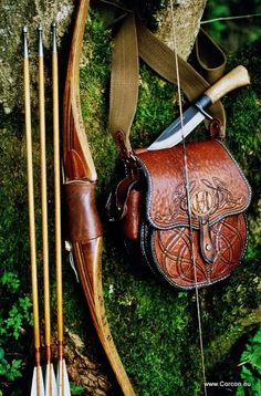 an arrow, bow and leather bag sitting on the ground