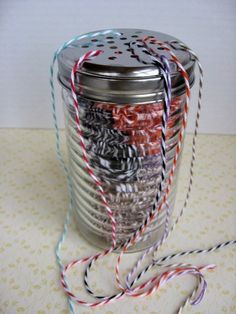 a jar filled with lots of different colored thread