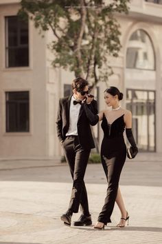 a man in a tuxedo walking next to a woman in a black dress