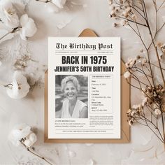 an old fashioned birthday card on top of a table next to flowers and dried branches