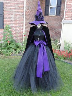 a black and purple witch costume on display in front of a brick building