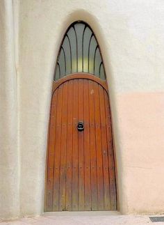 an orange door with arched glass on the side of a white stucco wall and floor