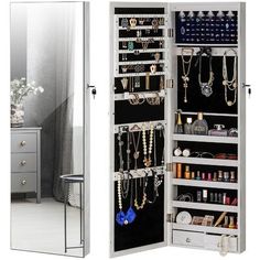 an open mirrored closet with jewelry hanging on the doors and drawers in front of it