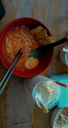 a bowl of ramen with chopsticks and bowls of soup on the side