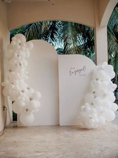 an arch with balloons attached to it in front of palm trees