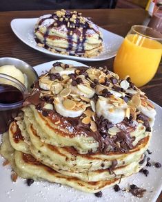 a stack of pancakes on a plate with chocolate sauce and banana slices next to it