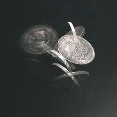 two different types of silver coins on a black surface with one being tied up to the other