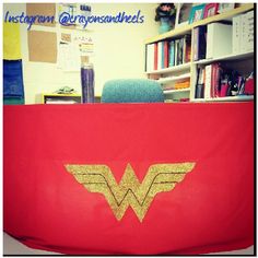 the wonder woman logo is on top of a red blanket in an office cubicle