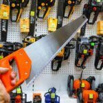 a person holding a pair of scissors in front of a display of tools