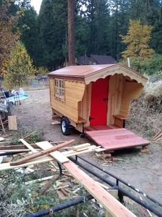 a small wooden trailer with a red door in the middle of some wood planks