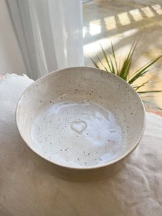 a white bowl sitting on top of a table next to a potted green plant