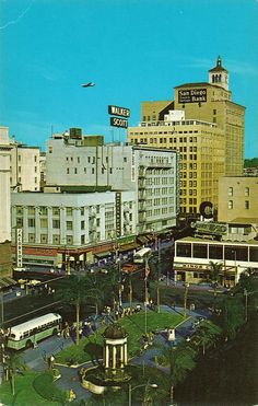 the city is full of tall buildings and traffic in this old photo, with an airplane flying overhead