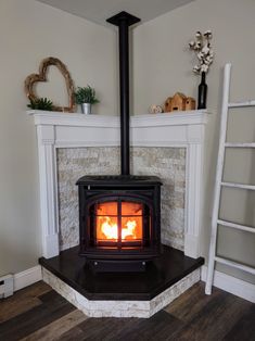 a wood burning stove in a living room next to a ladder and potted plant