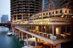 a restaurant on the side of a river in front of a large building with balconies