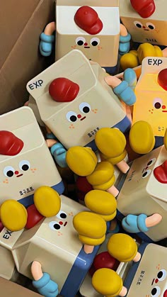 many toy figures are stacked together in a cardboard box with eyes and noses on them