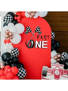 the balloon arch is decorated with black, white and red balloons that read fast one