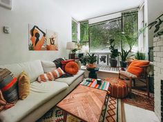 a living room filled with furniture and lots of plants in the window sill area