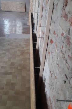 an empty room with brick walls and flooring in the foreground, next to a doorway