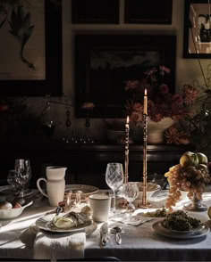 a dining room table is set with dishes and candles