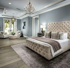 a large bedroom with blue walls and white furniture in the center is an elegant chandelier