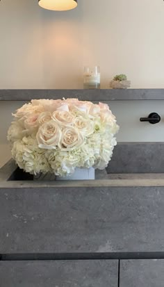 a bouquet of white flowers sitting on top of a counter next to a light fixture