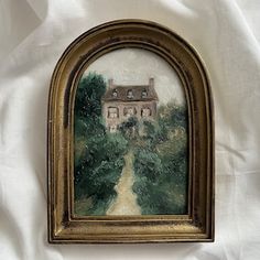 an old painting hanging on the wall in front of a white cloth covered bed sheet