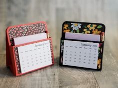 two small desk calendars sitting next to each other on top of a wooden table