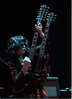 a man with long hair playing an electric guitar