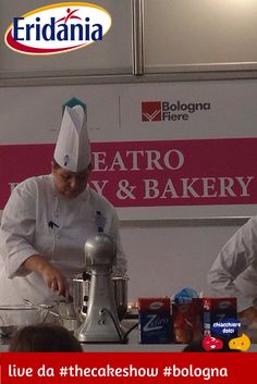 two chefs preparing food in front of a sign