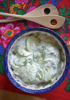 a blue bowl filled with cucumbers and sour cream