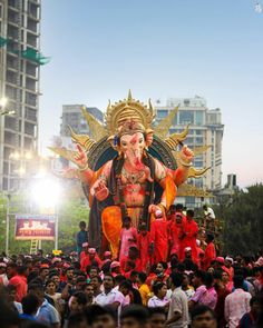 a large statue of the god ganesh is surrounded by people on a city street