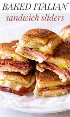 several sandwiches stacked on top of each other on a white plate with wax paper around them