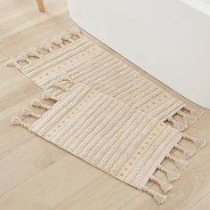 a white bath tub sitting next to a beige rug on top of a wooden floor